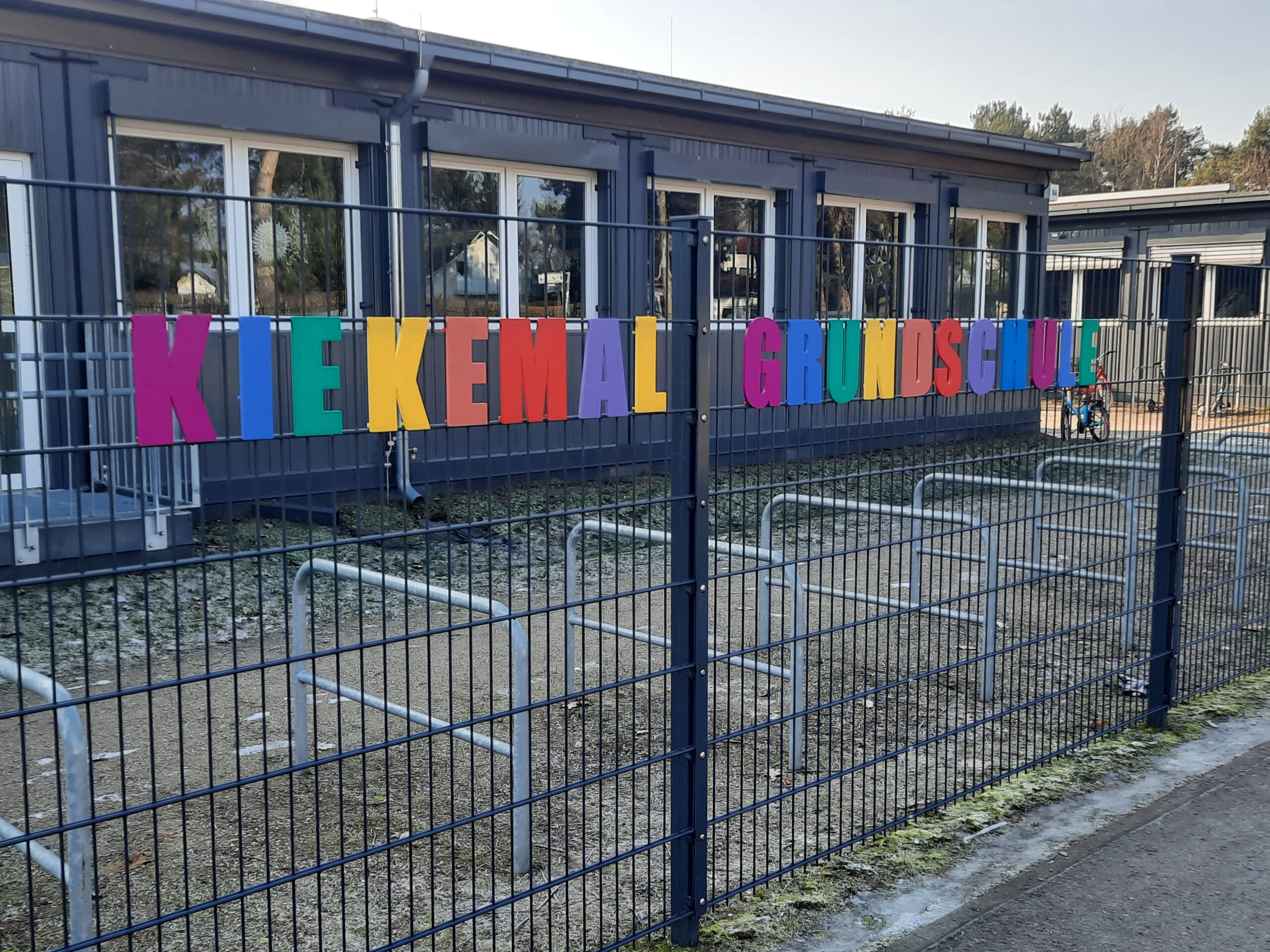 Schulname am Zaun der Filiale